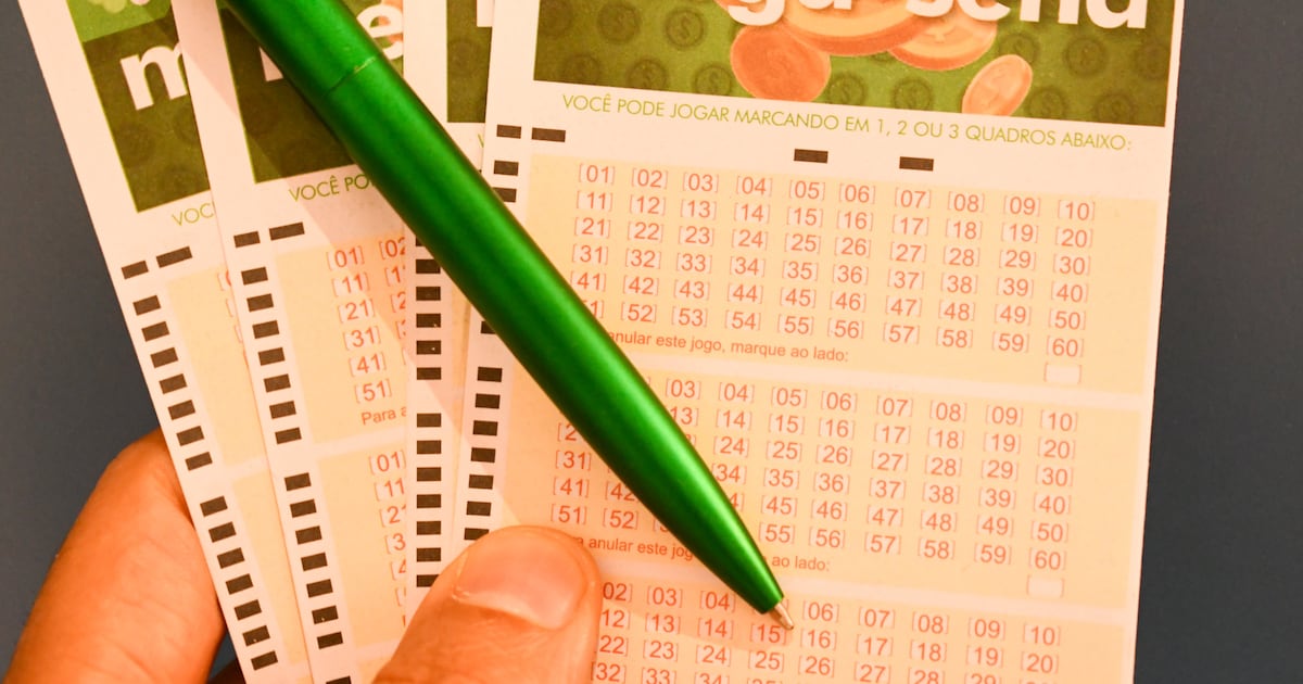 Jornalista segurando papel com números da Mega-Sena acumulada.