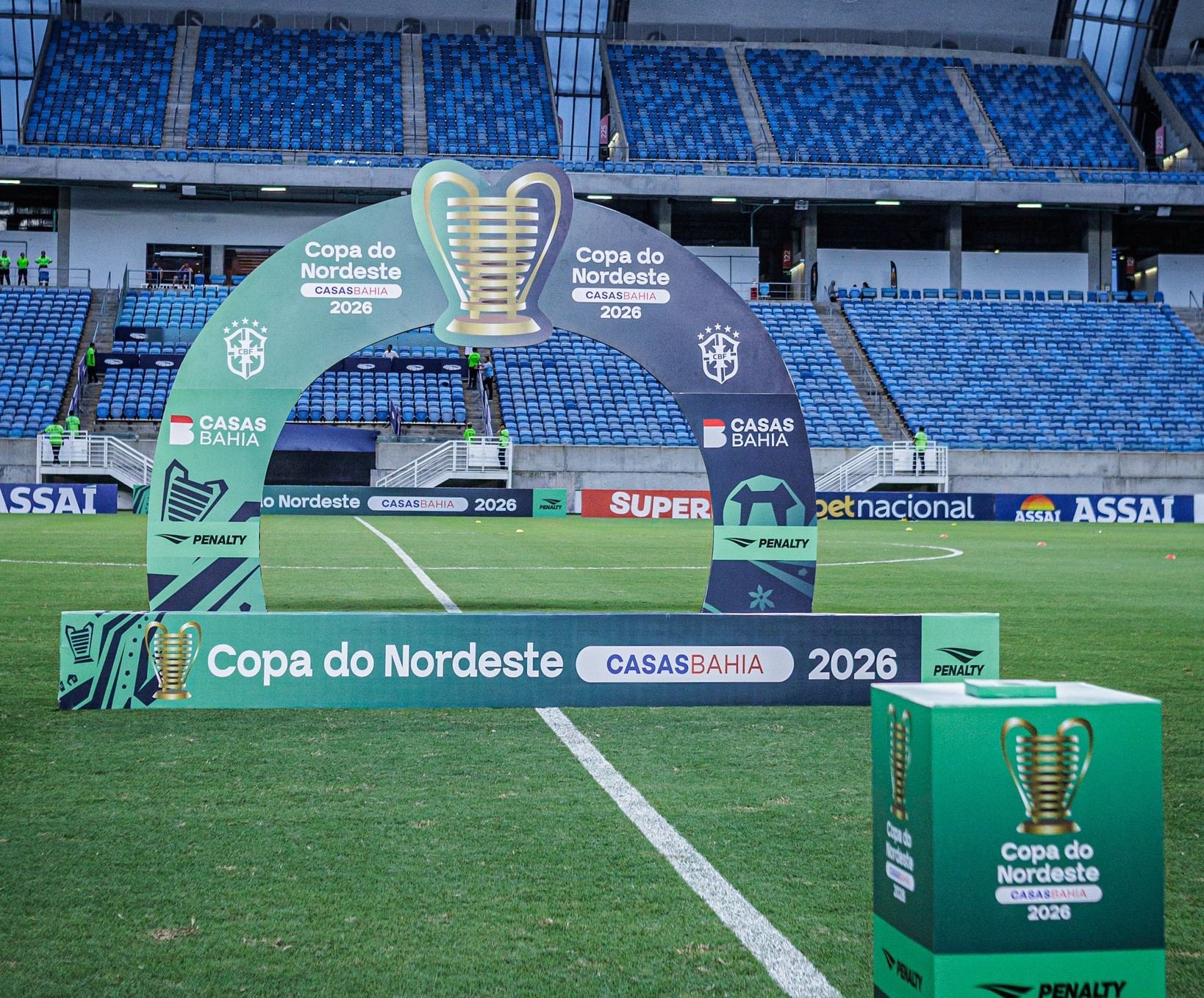 Jornalista sentado à mesa, com papel e lápis, revisando notícia de futebol.