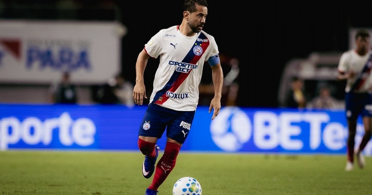 Jornalista segurando um jornal com manchete sobre eliminações da Bahia em uma temporada esportiva.