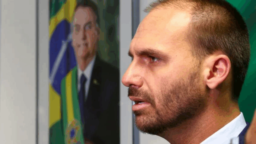 Homem de terno e gravata fala em frente a uma mesa com um papel com o valor de R$ 134 milhões.