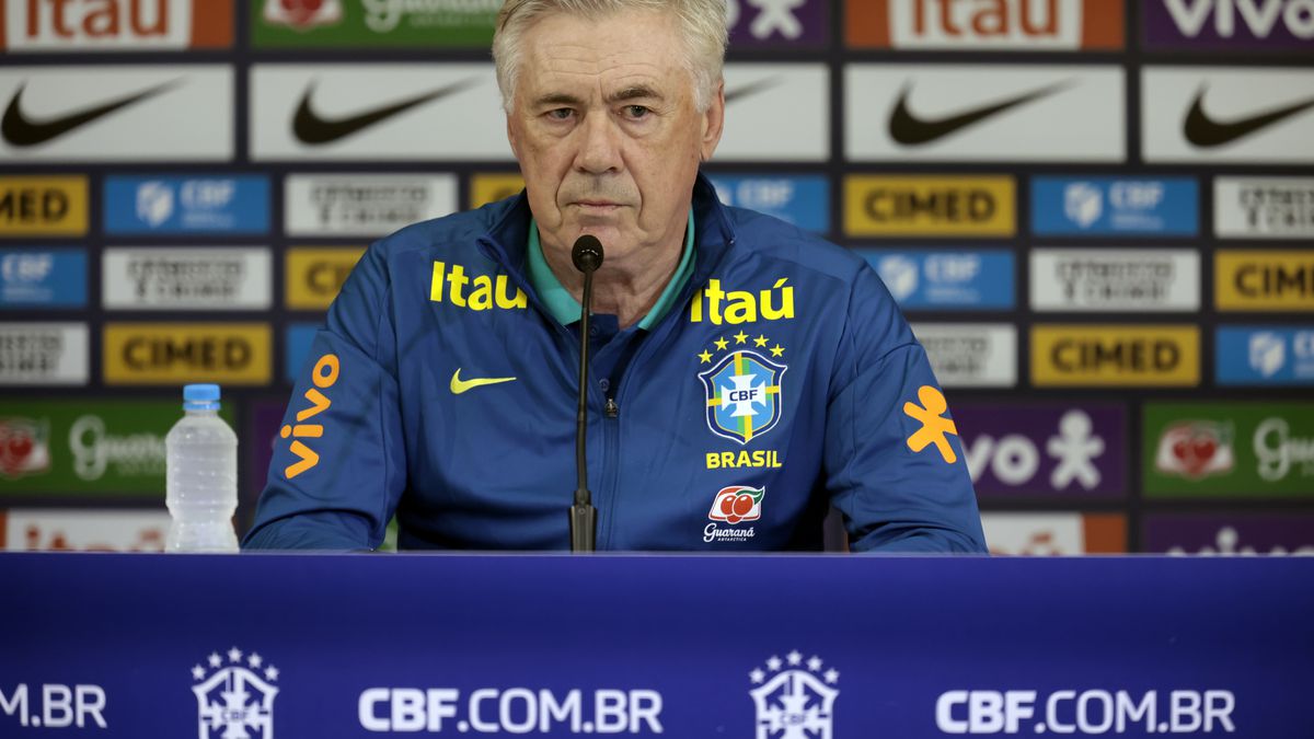 Jornalista segurando papel com lista de convocados da Seleção Brasileira para a Copa, com fundo de estúdio de TV.