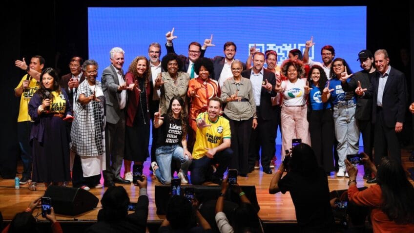 Líderes políticos Flávio e Vorcaro ao lado do presidente Lula, discutindo estratégia digital.