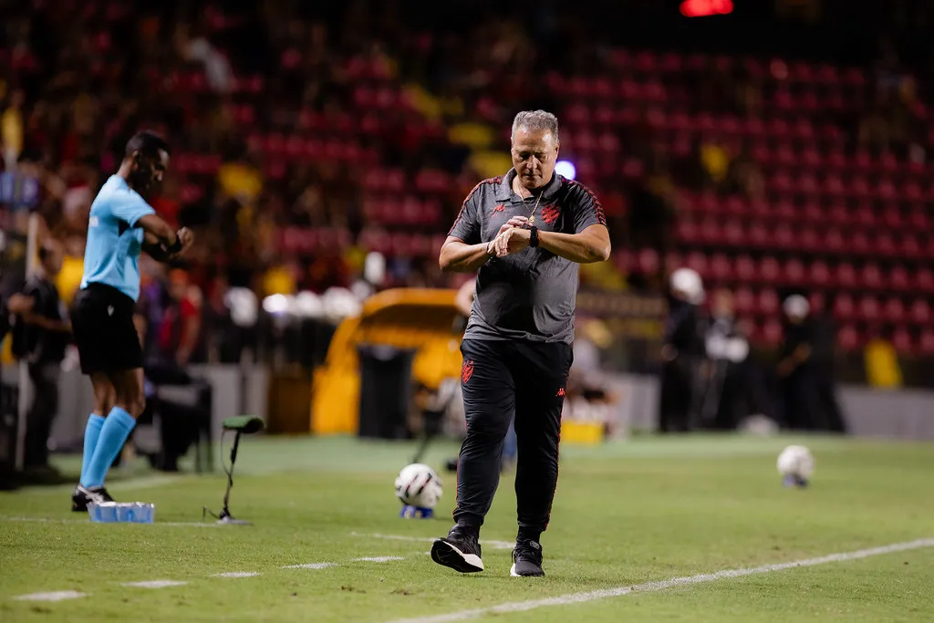 Técnico de futebol examina o campo após tropeço em jogo da Série B.