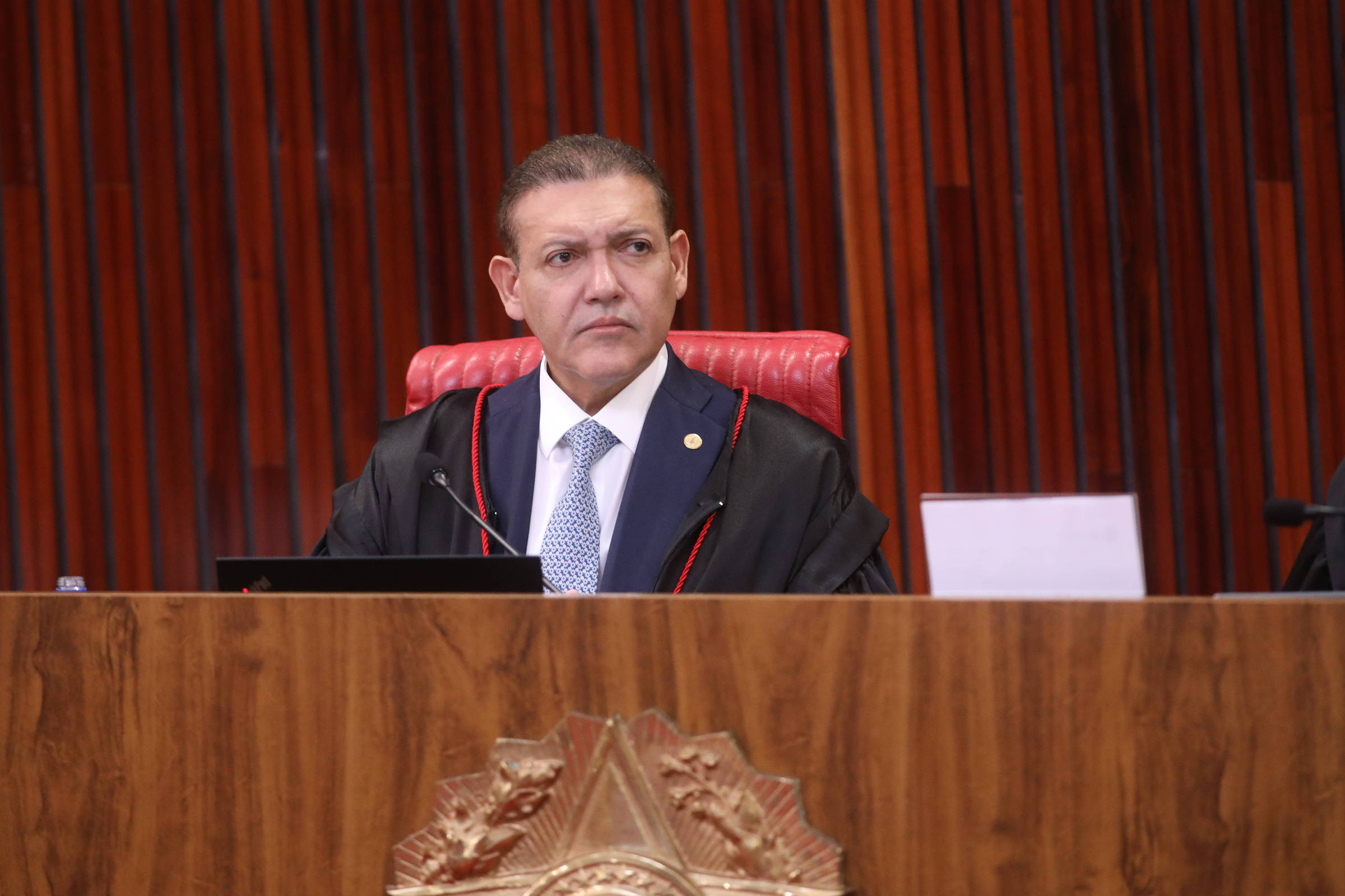 Homem autoritário com expressão de confusão em ambiente de jornalismo.