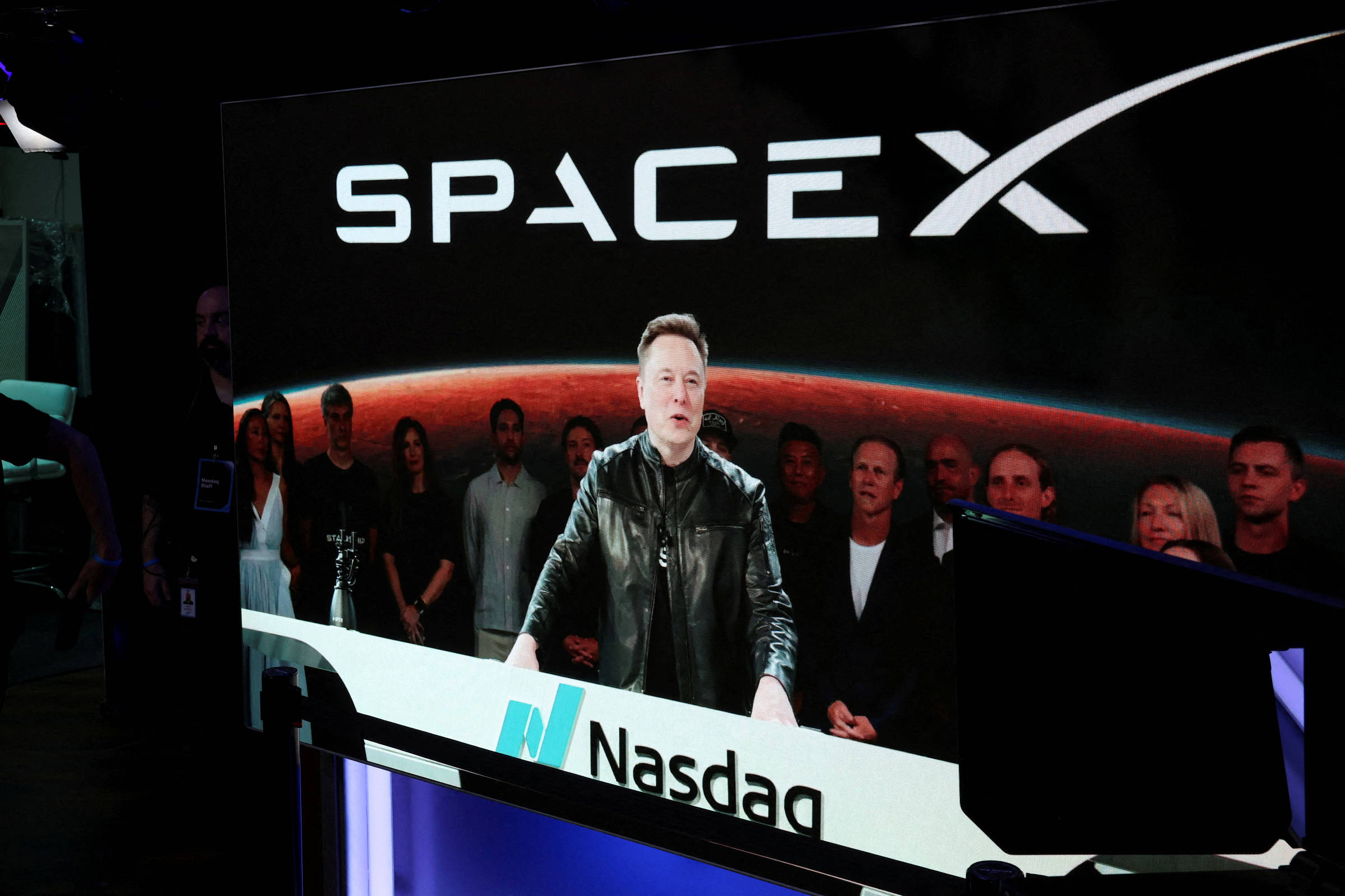 Tela de um jornal impresso com gráficos financeiros e uma linha de queda mostrando ações da SpaceX.