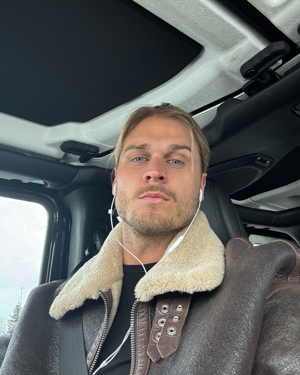 Jogador de futebol famoso sentado em estúdio de arte, com lápis na mão e olhar pensativo.