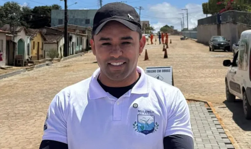 Prefeito sentado à mesa de reunião, com documentos e relatórios em cima.