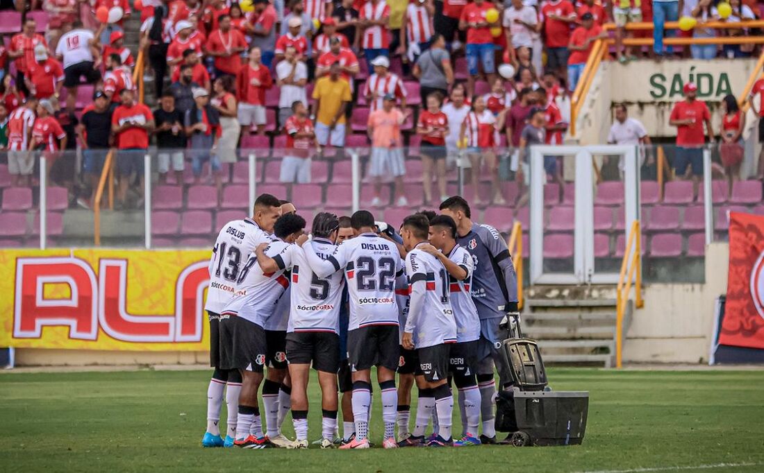 Interior da Arena Batistão em Santa Cruz, com iluminação intensa e público em pé.
