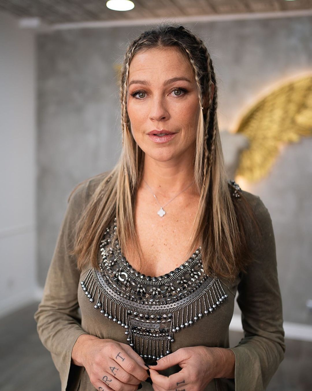 Mulher influente sentada em hospital, com expressão de dor e preocupação, ao lado de seu marido.