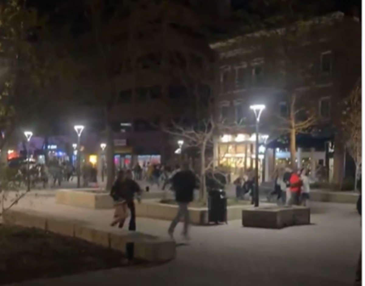 Cena de tiroteio na Universidade de Iowa com pessoas correndo e sirenes de ambulância.