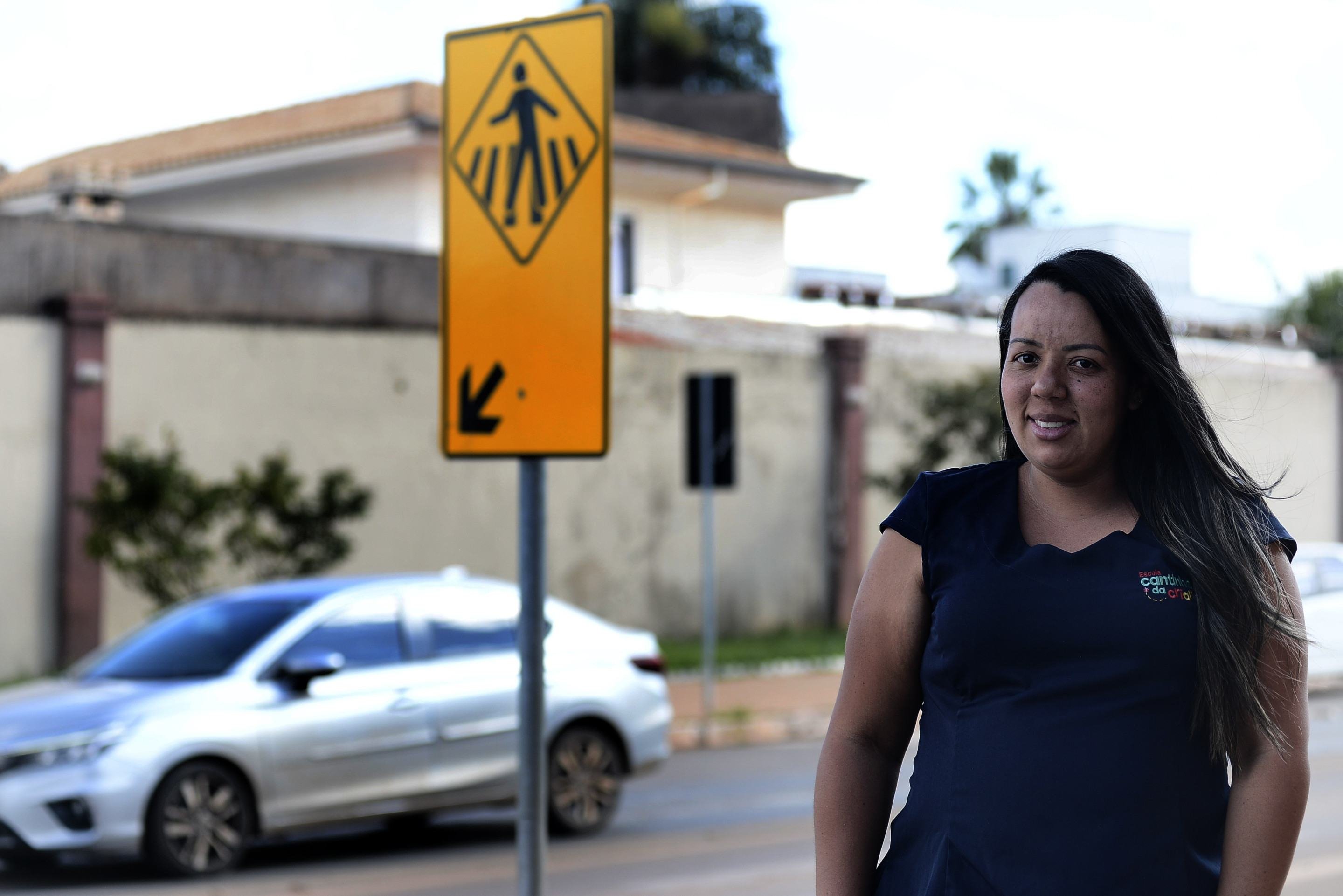Faixa de pedestres em cidade movimentada, com pessoas caminhando e carros passando ao lado.