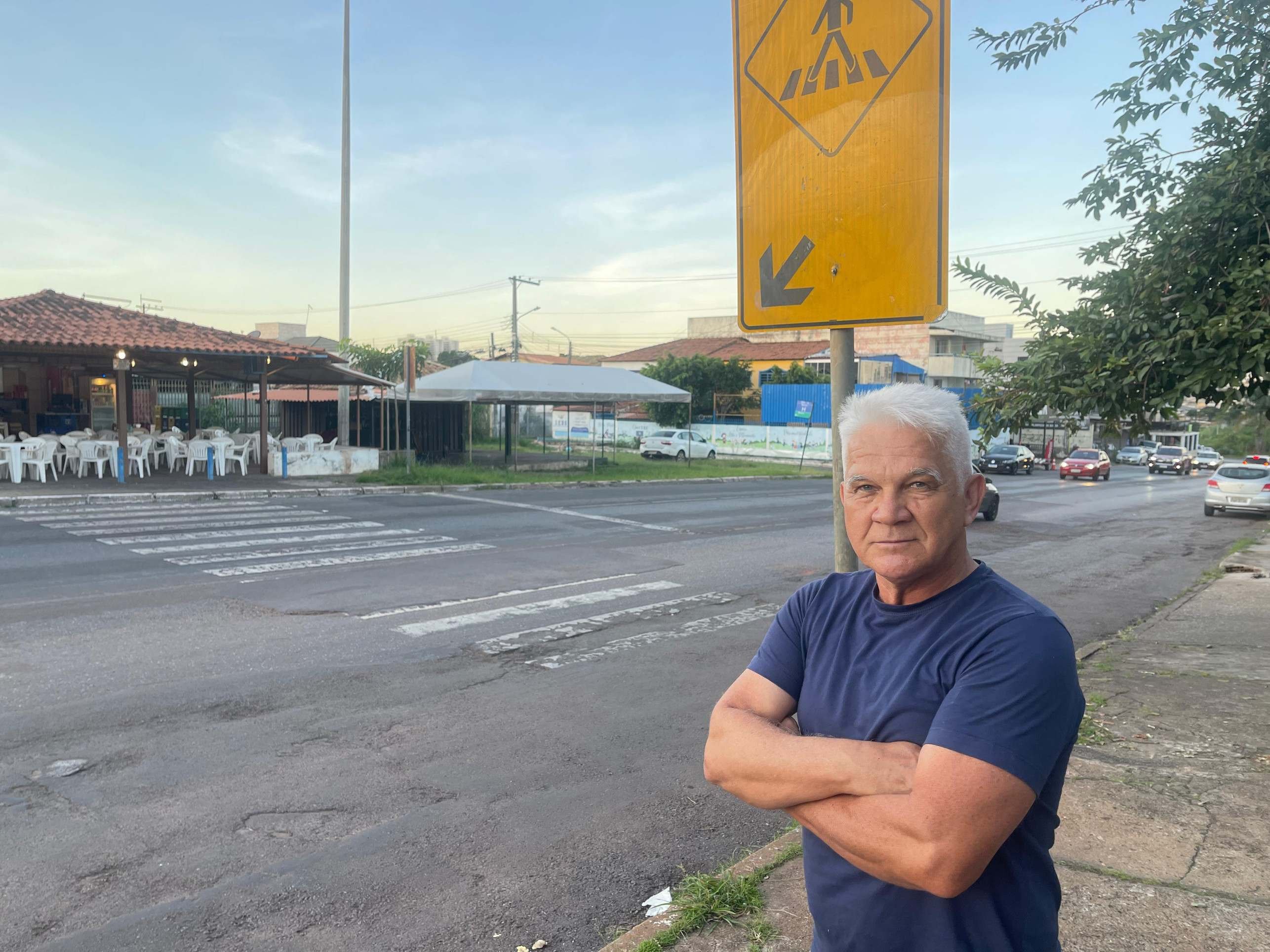 Faixa de pedestres em cidade movimentada, com pessoas caminhando e carros passando ao lado.