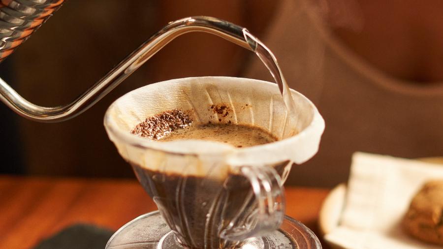 Mulher bebendo café enquanto lê um artigo sobre nutrientes afetados pela bebida.