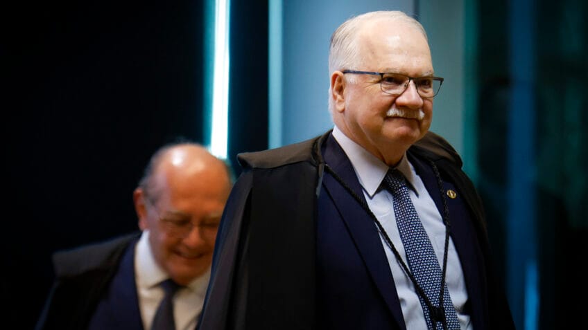 Ministro Gilmar Ribeiro sentado à mesa de julgamento, com expressão de desafio, enquanto outros ministros assistem.