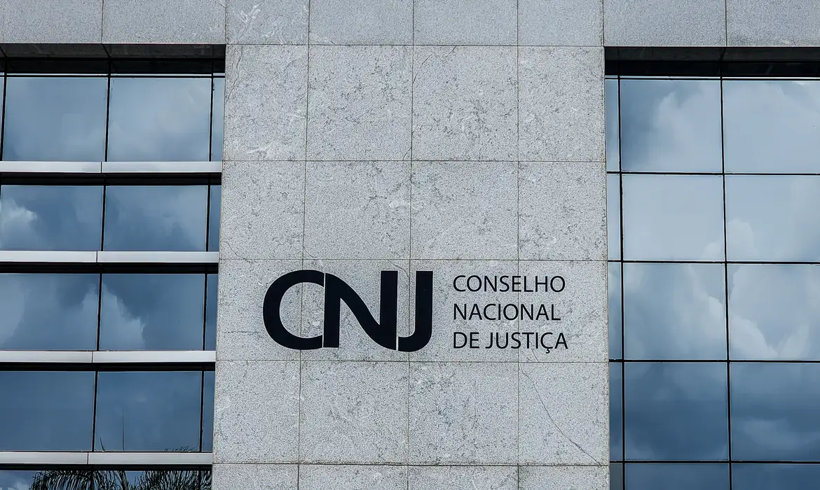 Devedores em frente a um computador com tela de bloqueio judicial automático.