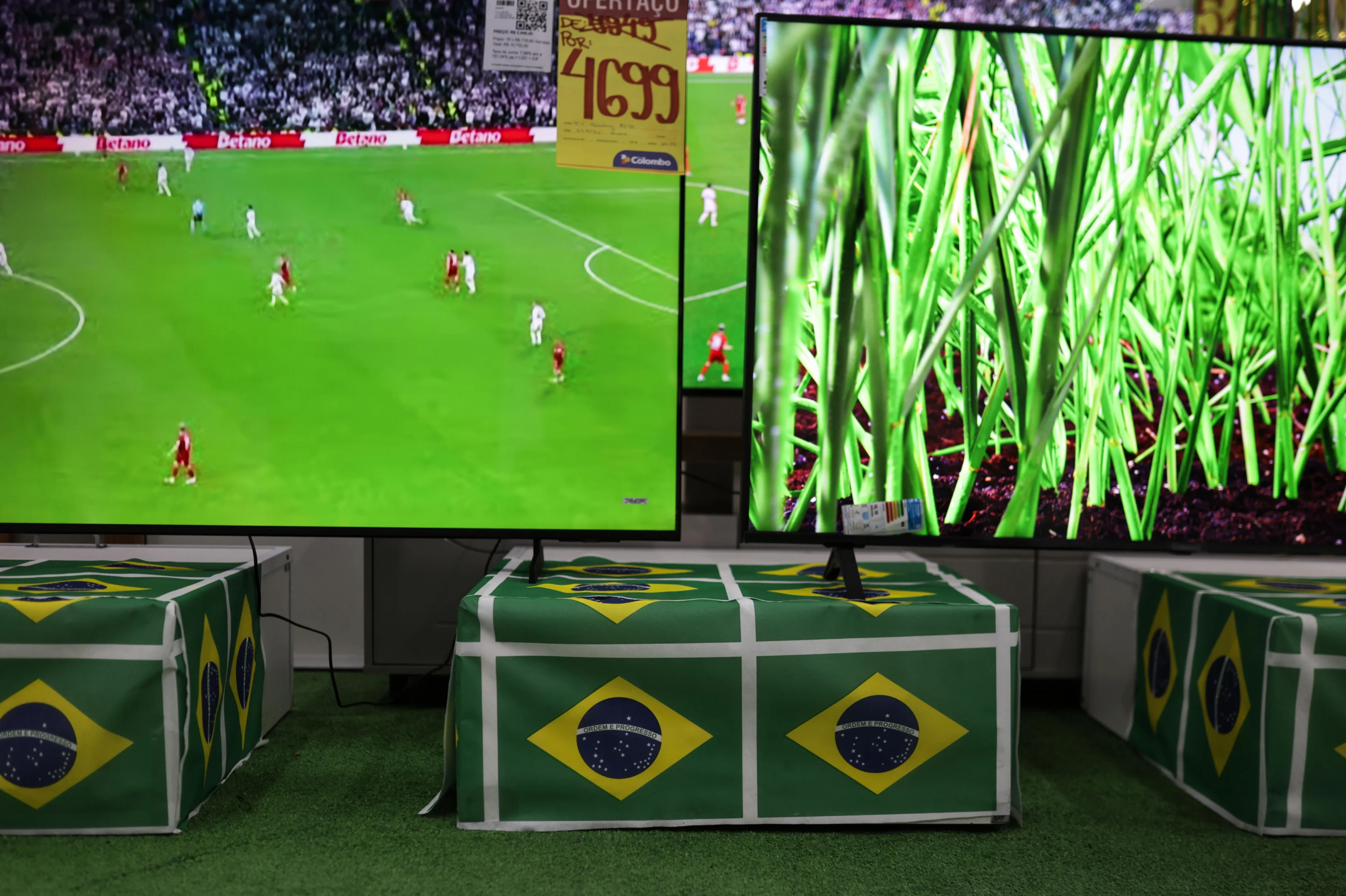 Público assiste a transmissão de uma partida de futebol na Copa do Mundo 2026 em uma sala com tela grande.