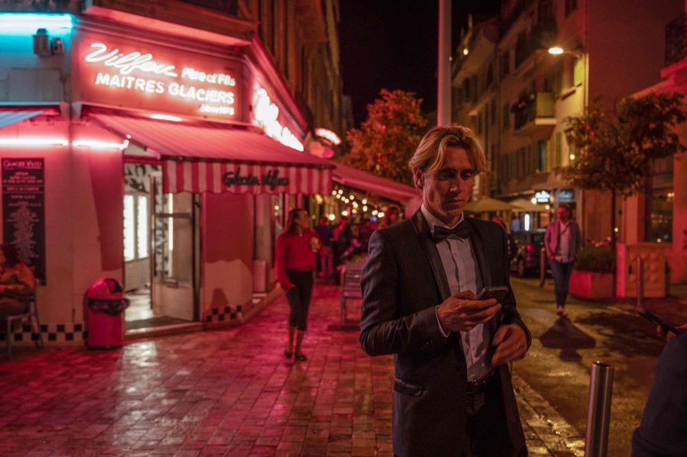 Cinéfilos sentados em calçada vermelha, assistindo a filmes no Festival de Cannes.