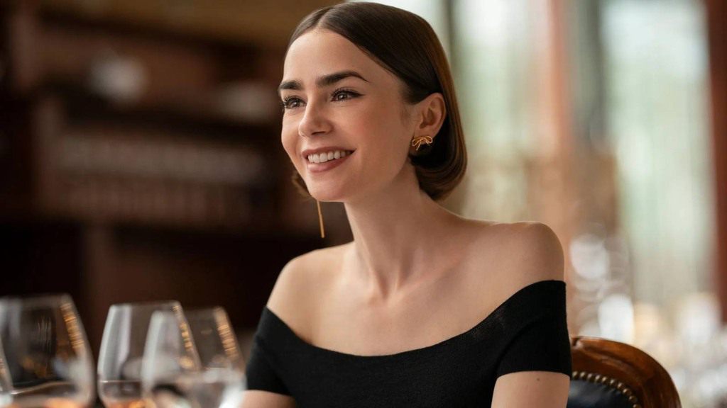Mulher sentada à mesa de redação, lendo jornal com manchete sobre Emily in Paris.