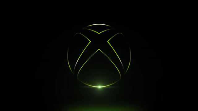 Executivo de videogames sentado à frente de uma mesa com uma XBOX e um sorriso confiante.