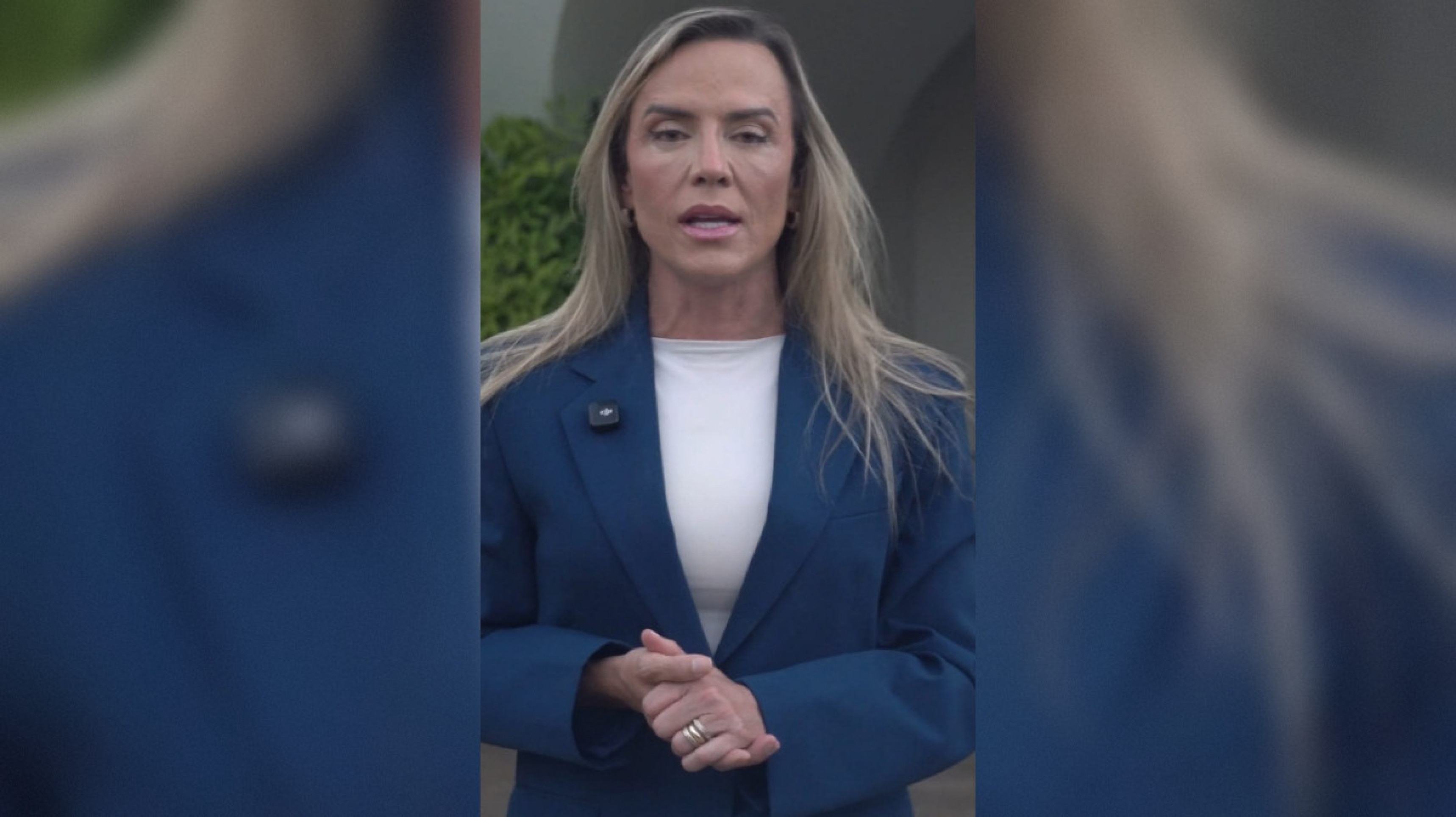Mulher reumatologista sentada em consultório médico, falando com paciente.