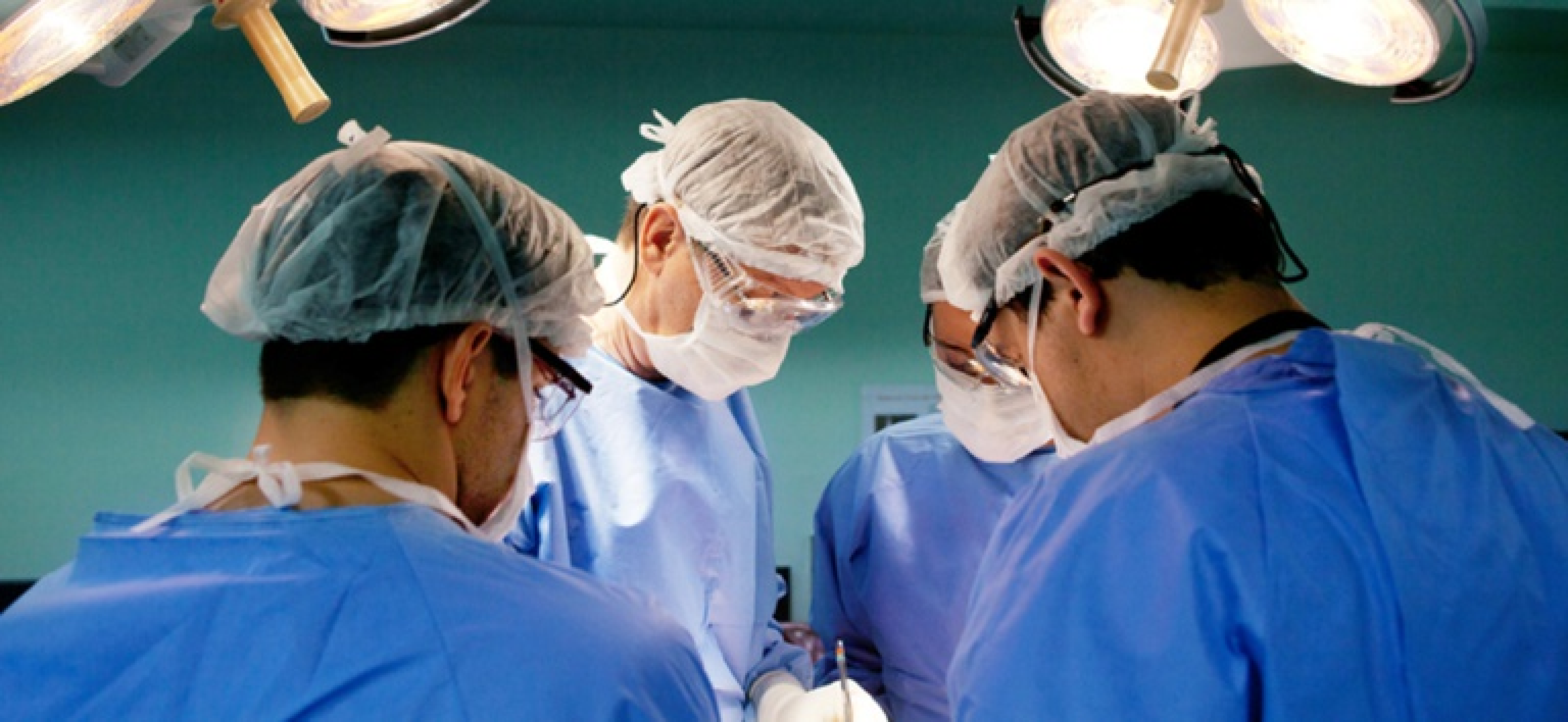 Mulher reumatologista sentada em consultório médico, falando com paciente.