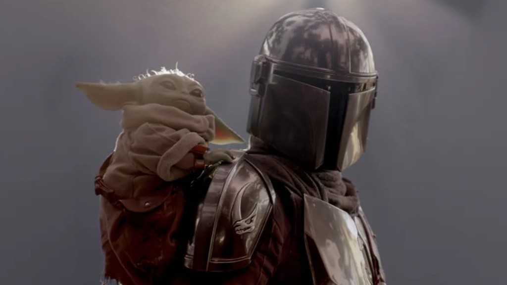 Um jornalista sentado à mesa de edição, com um tablet em mãos, lendo notícias sobre a possível 4ª temporada de The Mandalorian.