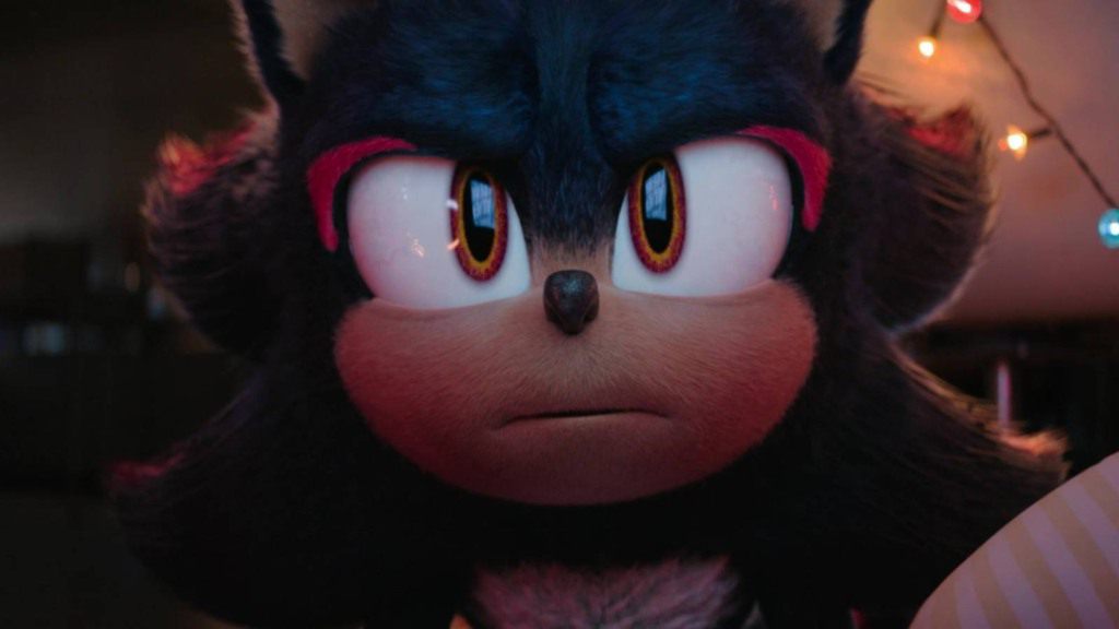 Jornalista lê notícia sobre retorno de Shadow em Sonic 4, com expressão de surpresa e preocupação.