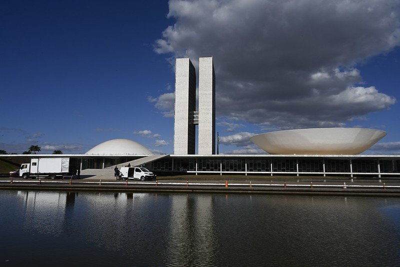 Políticos em conclave, sorrisos forçados, enquanto o governo é acusado de compra de votos.
