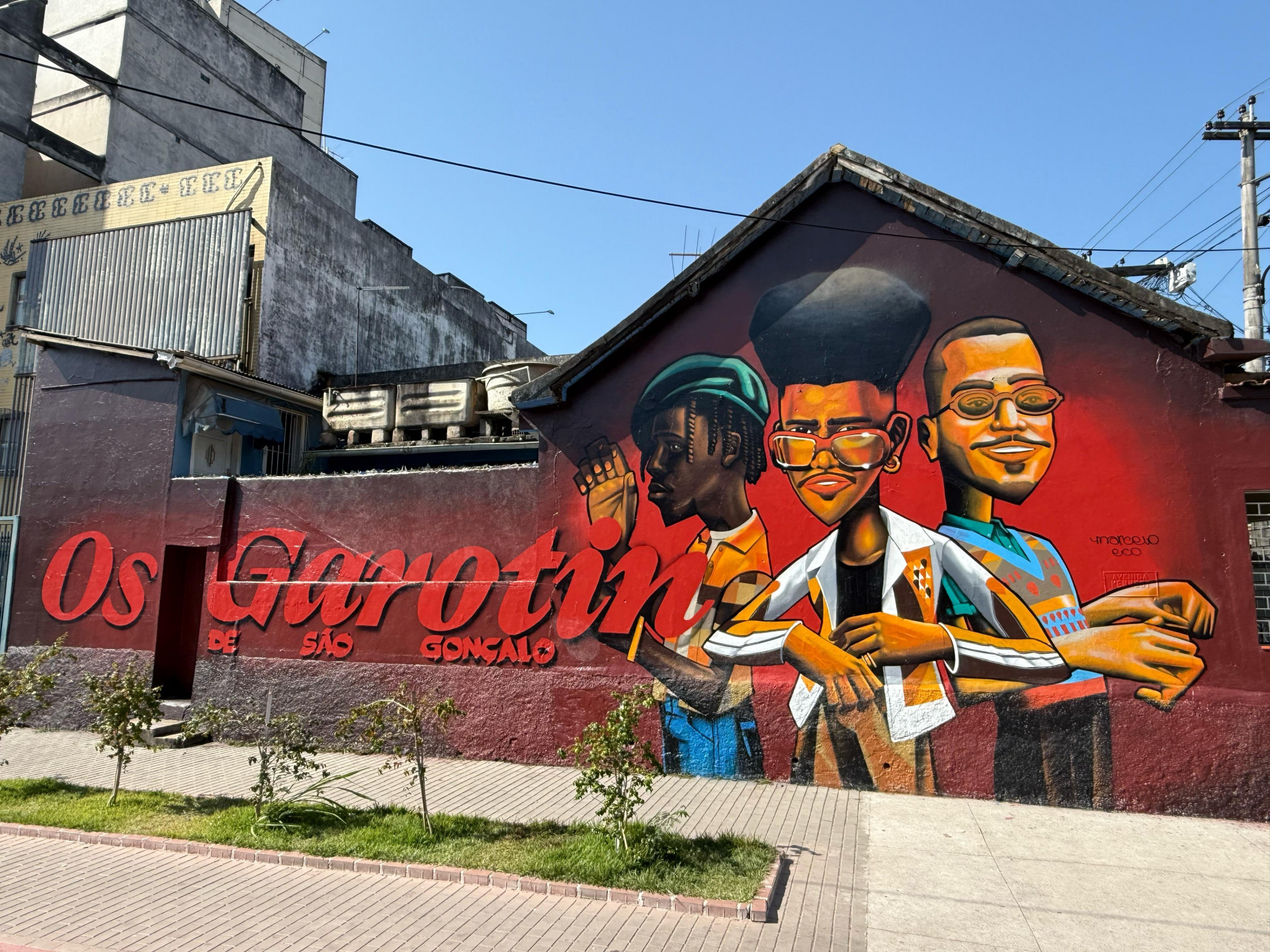 Trio de música "Os Garotin" posa ao lado de estátua de Cria de São Gonçalo.