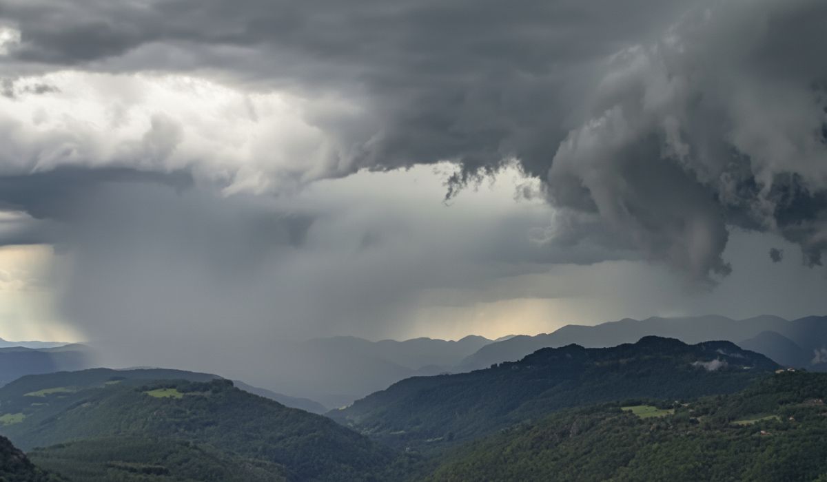 Imagem de um mapa de SC com nuvens escuras e raios em um fundo de cores azuis e cinzas.