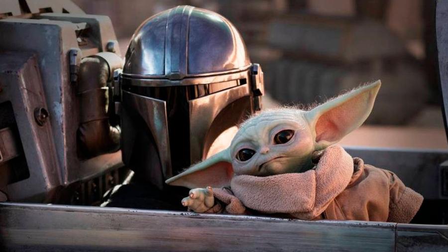 Ator em frente a uma mesa de notícias, segurando um jornal com manchete sobre o novo filme "Star Wars".
