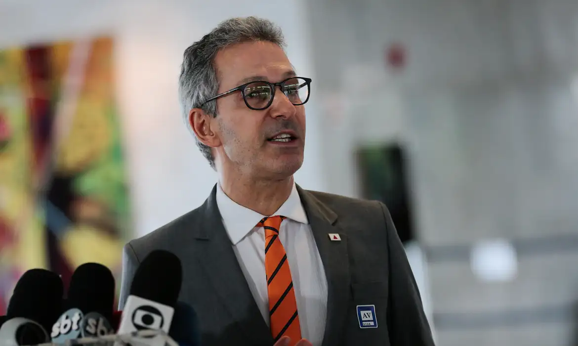 Jornalista segurando uma cópia de um jornal com manchete sobre candidatura de Flávio.