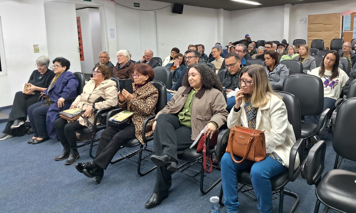 Equipe de jornalistas reunida em torno de uma mesa com cartilhas e documentos.