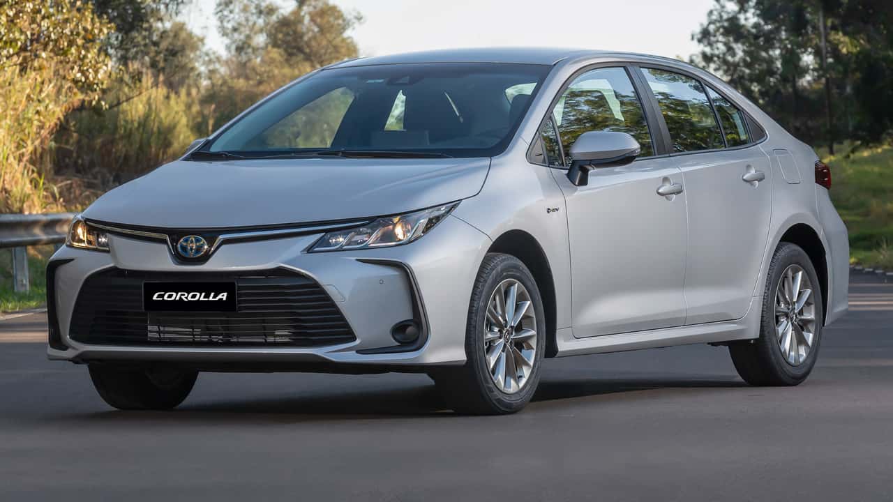 Imagem de uma fábrica da Toyota fechada com uma picape híbrida ao fundo.
