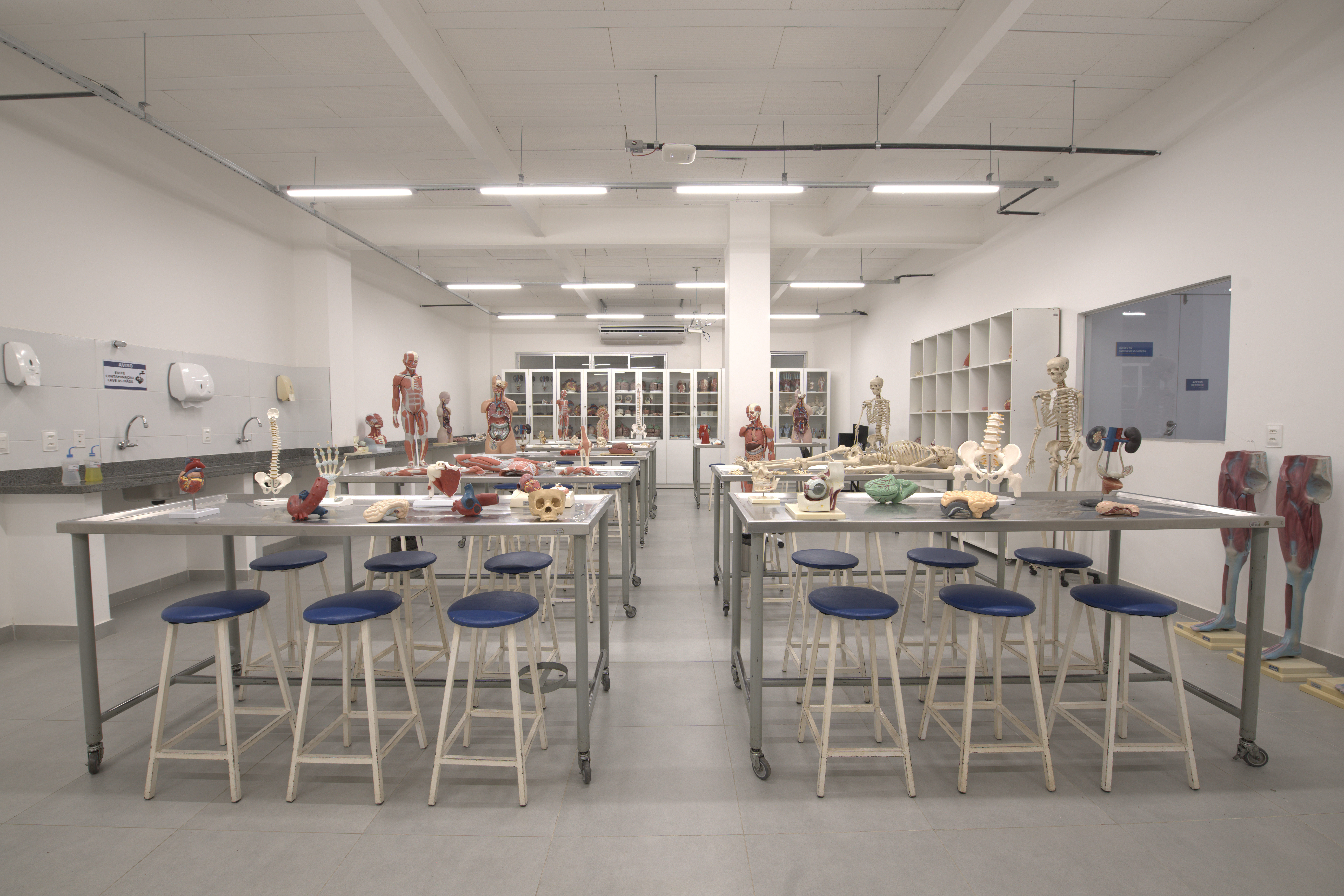 Estudantes em aula, com professores e materiais educacionais em uma sala de aula moderna.