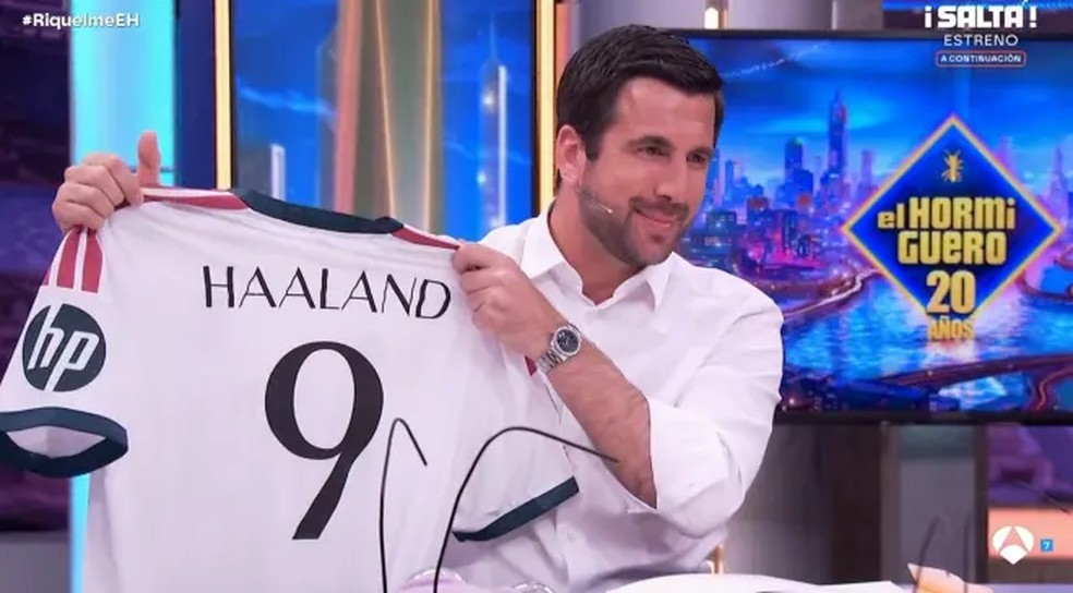 Jornalista segurando papel com notícia de negociação de transferência de Haaland para o Real Madrid