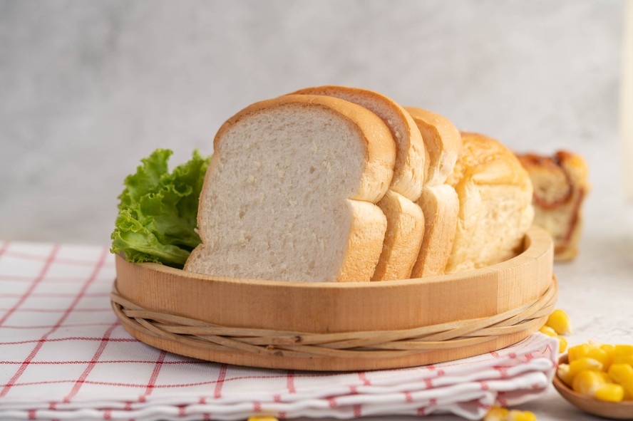 Imagem de um pão com ingredientes químicos visíveis em uma mesa de laboratório.