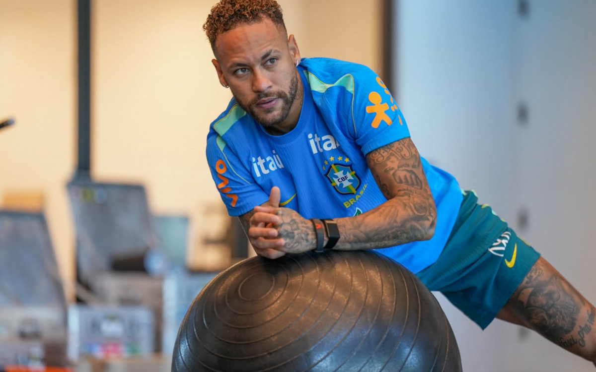 Equipe de futebol em campo, jogadores concentrados e treinadores em tom sério, cenário de jogo importante.