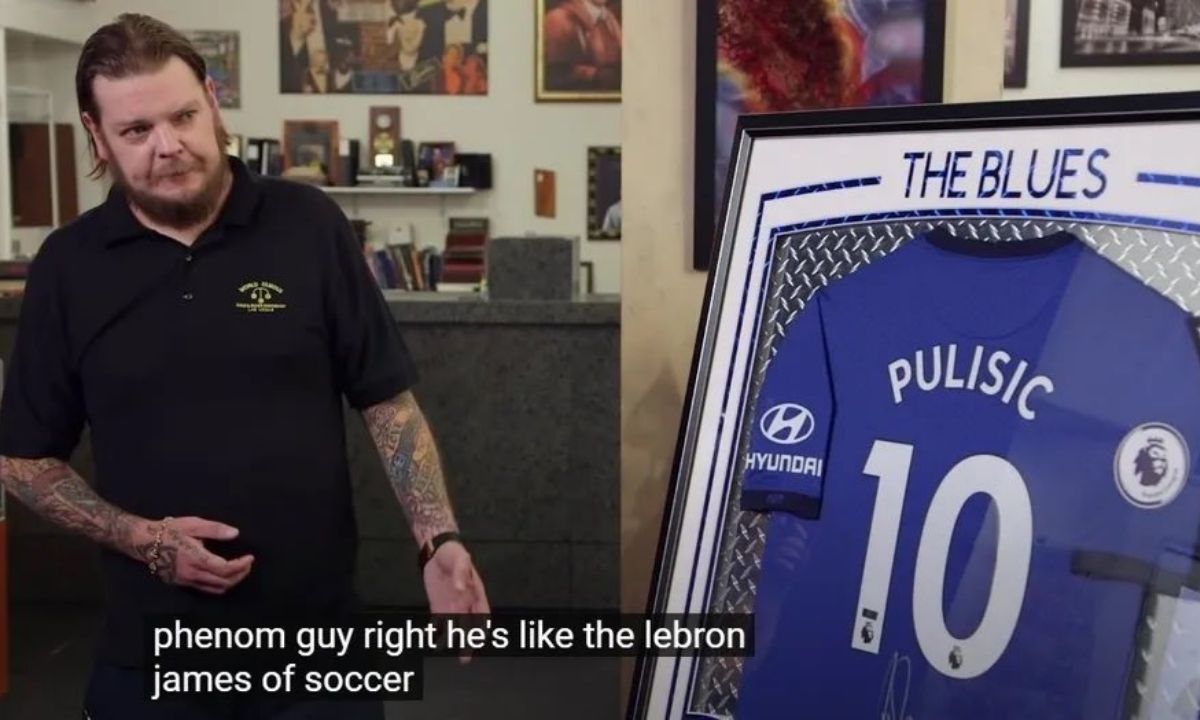 Lebron James, jogador de basquete, tenta chutar bola de futebol em campo de jogo.