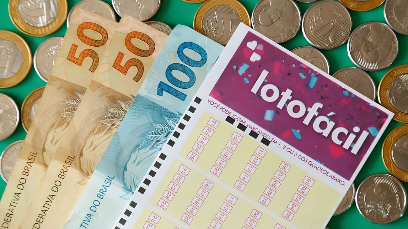 Três pessoas celebram ao lado de uma grande tela exibindo números da Lotofácil.