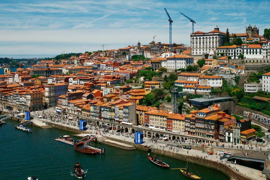 Trabalhadores em construção em Portugal, com canteiros de obras ao fundo.