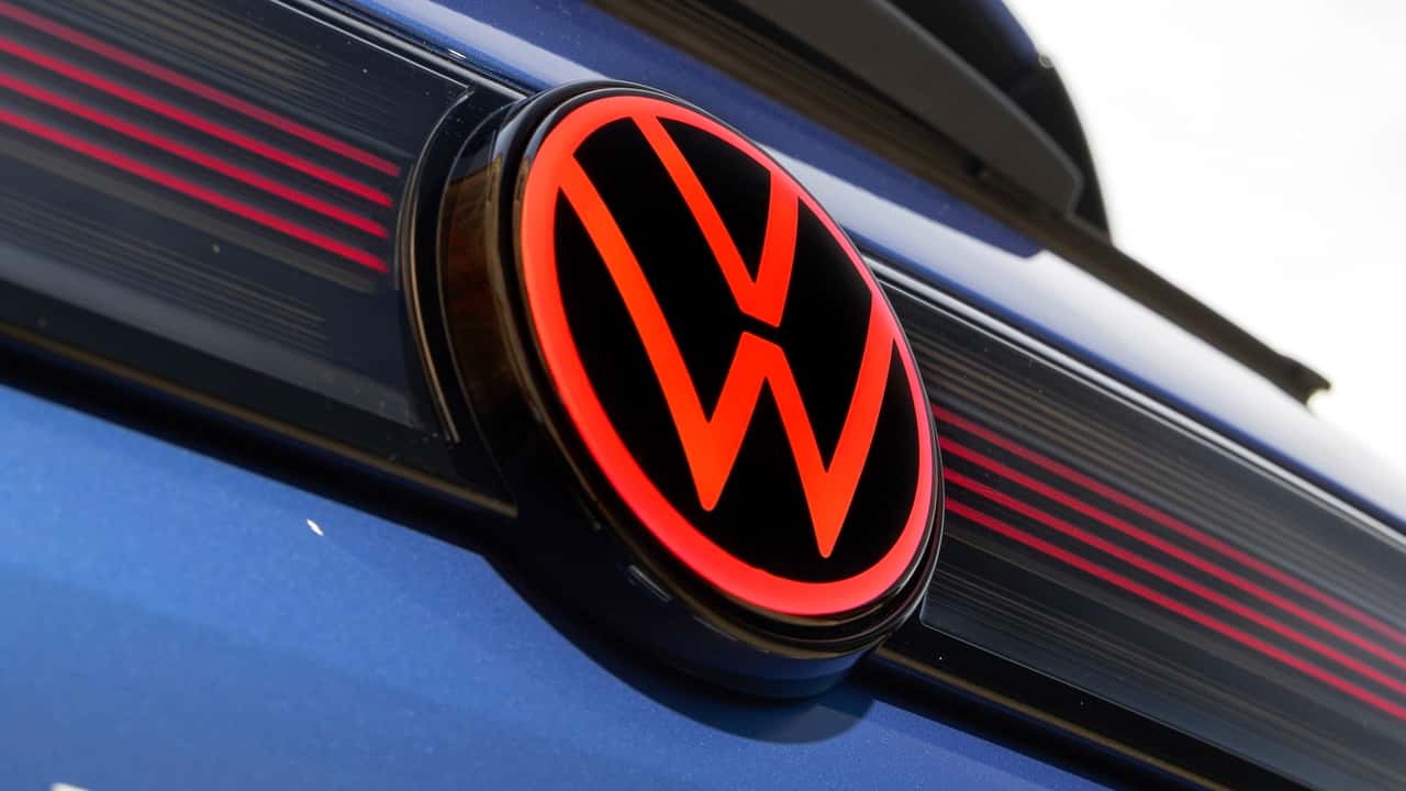 Imagem de uma linha de montagem da Volkswagen com veículos em diferentes estágios de produção.