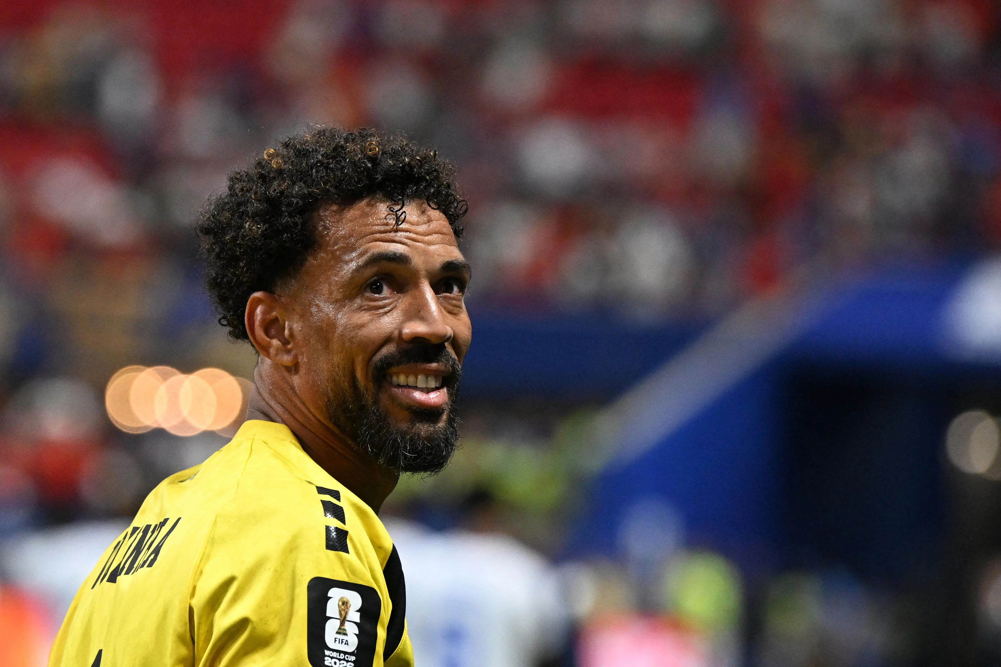 Jogador de futebol sentado em banco de campo, com uniforme de Colo-Colo e expressão de desapontamento.
