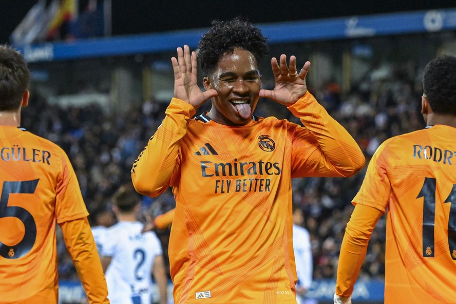Jovem jogador Endrick em ação no campo de futebol, com uniforme do Real Madrid, em jogo amistoso.